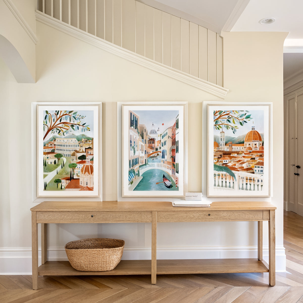 Three Italy travel prints above an oak console table in an entryway