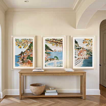 Three Amalfi Coast prints above an oak console table in an entryway