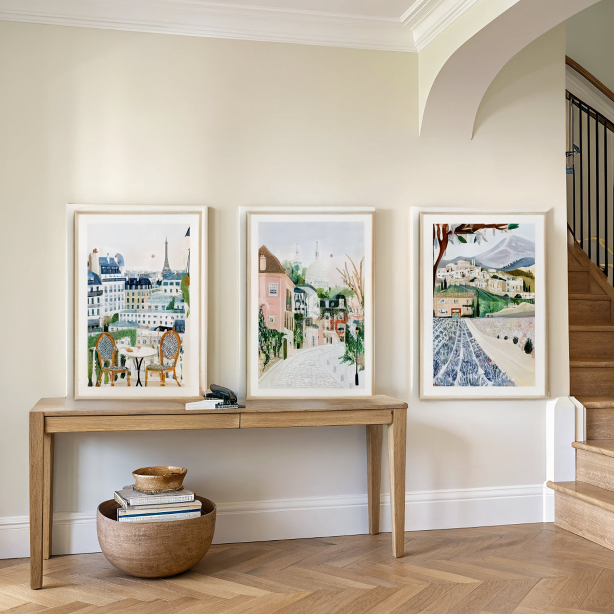 Three France travel prints above an oak console table in an entryway